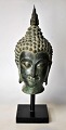Buddha-Büste 
aus Bronze, 20. 
Jahrhundert. 
Auf einem 
Holzsockel. 
Höhe: 23 cm. H. 
inkl. Fuß: 32.